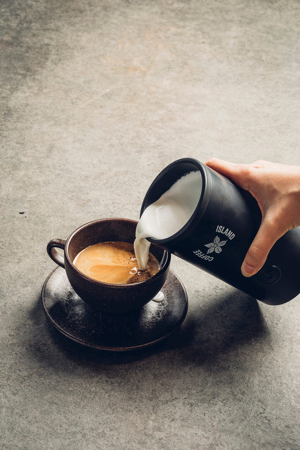 A woman pouring milk into a coffee island coffee.