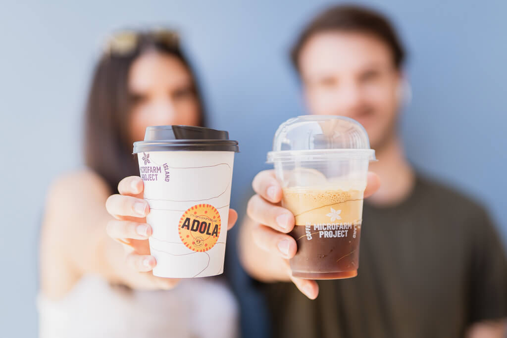 A man and a woman holding Coffee Island's ethiopia adola cups. 